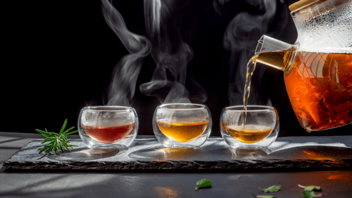 a decorative photo of steaming tea poured into glasses against a black background.
