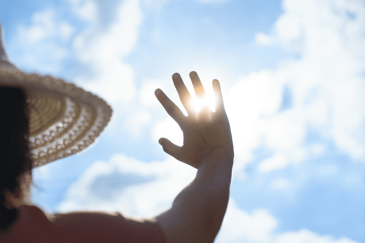 image of sun shining through someone's fingers