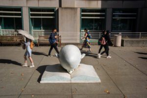 Students walk by Bookhead in front of the UC Davis Shields Library. Bookhead is the only Egghead sculpture tinted a light blue. (UC Davis)